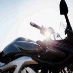 Particolare di una moto scura al sole