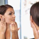 Donna che mette il fondotinta davanti uno specchio