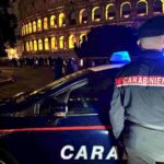 Carabiniere di spalle con macchina dei carabinieri e sullo sfondo il Colosseo